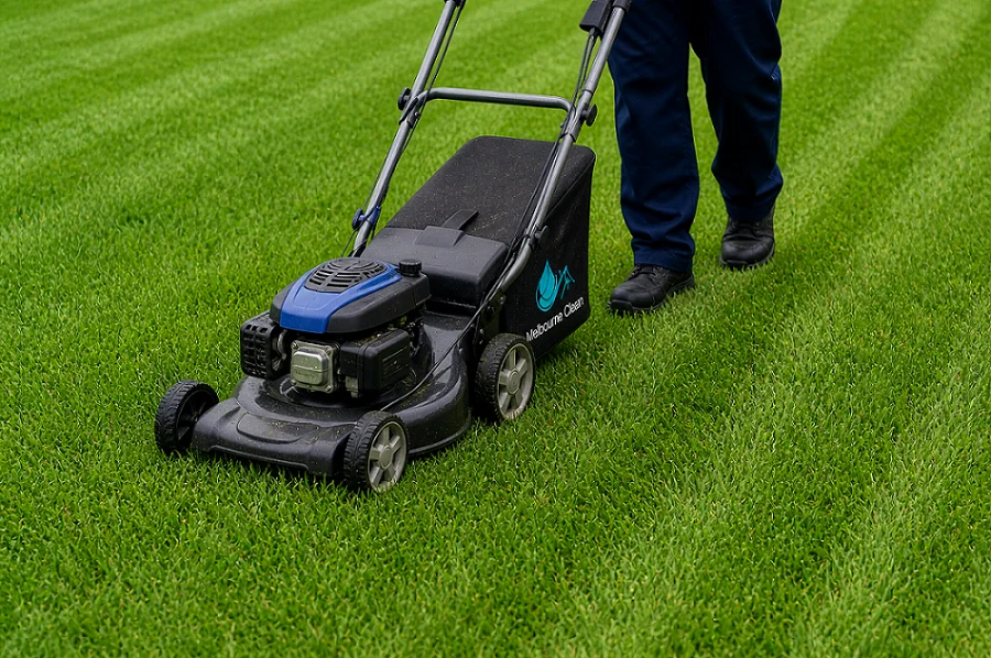 Home 20 A person in dark pants is pushing a modern, blue and black lawnmower across a freshly mowed, vibrant green lawn.